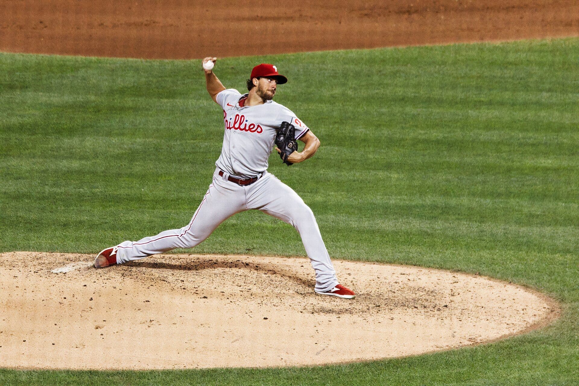 Aaron Nola of the Philadelphia Phillies in mid-delivery on the mound, wearing a gray road uniform with the Phillies script and a red cap.